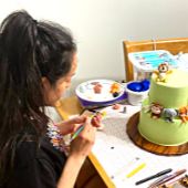 Julie decorating a two-teired cake at her decoration station 